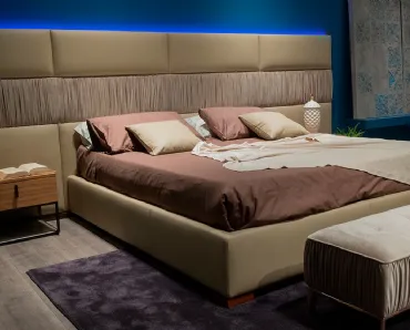 Letto con testiera modulare e morbida in cui le superfici sono scandite dall’alternarsi di rivestimento liscio e plissettato Infinity di Novaluna